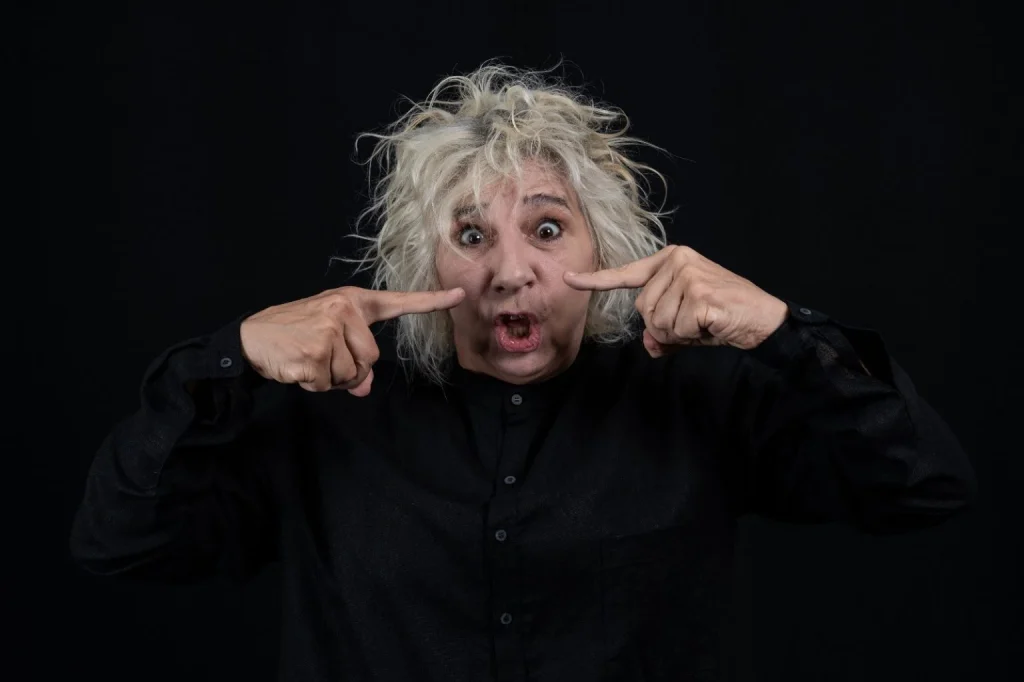 Agenda cultural Santos: cinema, teatro e exposições — imagem de Denise Stoklos em cena no espetáculo “Abjeto-Sujeito: Clarice Lispector por Denise Stoklos”, com expressão marcante e gesto de apontar, em fundo escuro.
