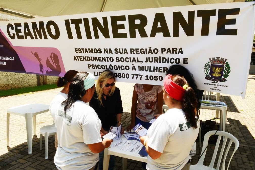 Equipe do Ceamo participa de ação de acolhimento na Praça, com banner “CEAMO ITINERANTE” e a mensagem de atendimento social, jurídico e psicológico a mulheres vítimas de violência em Campinas.