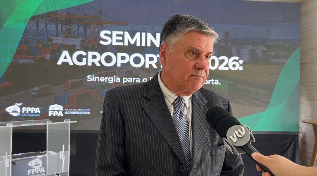 investimento em infraestrutura: Caio Morel, presidente executivo da Abratec, em entrevista ao microfone durante evento com painel “SEMIN AGROPOR 2026”. Ao fundo, imagens de infraestrutura e estande institucional.