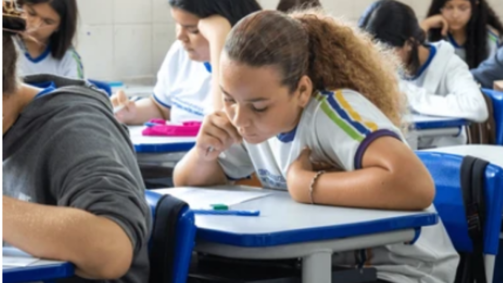 Alunos sentados em carteiras escolares realizando a prova do Enem em uma unidade da rede pública de ensino.