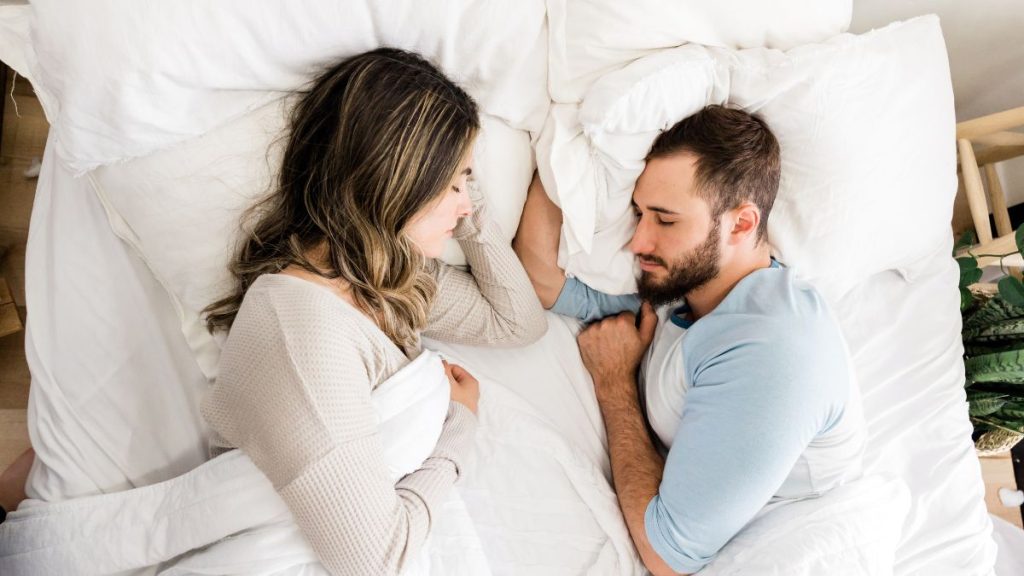 Casal deitado em camas separadas no mesmo quarto, ilustrando o conceito de divórcio do sono para melhorar a qualidade do descanso individual.
