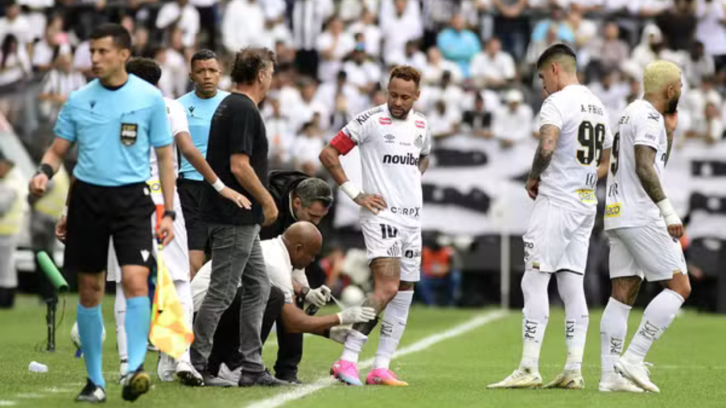 Neymar Jr. sentado no gramado recebendo atendimento médico da equipe do Santos durante a partida contra o Coritiba.