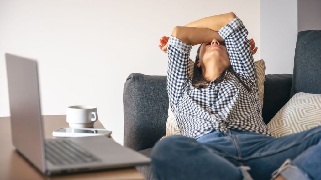 Pessoa sentada à mesa de trabalho com as mãos no rosto, representando o desgaste emocional e os sinais silenciosos que precedem o burnout.