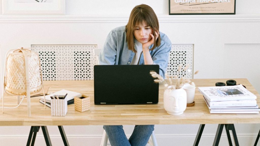 Colaborador em frente ao computador expressando cansaço físico e desânimo, exemplificando como o corpo reage ao estresse crônico no ambiente profissional.