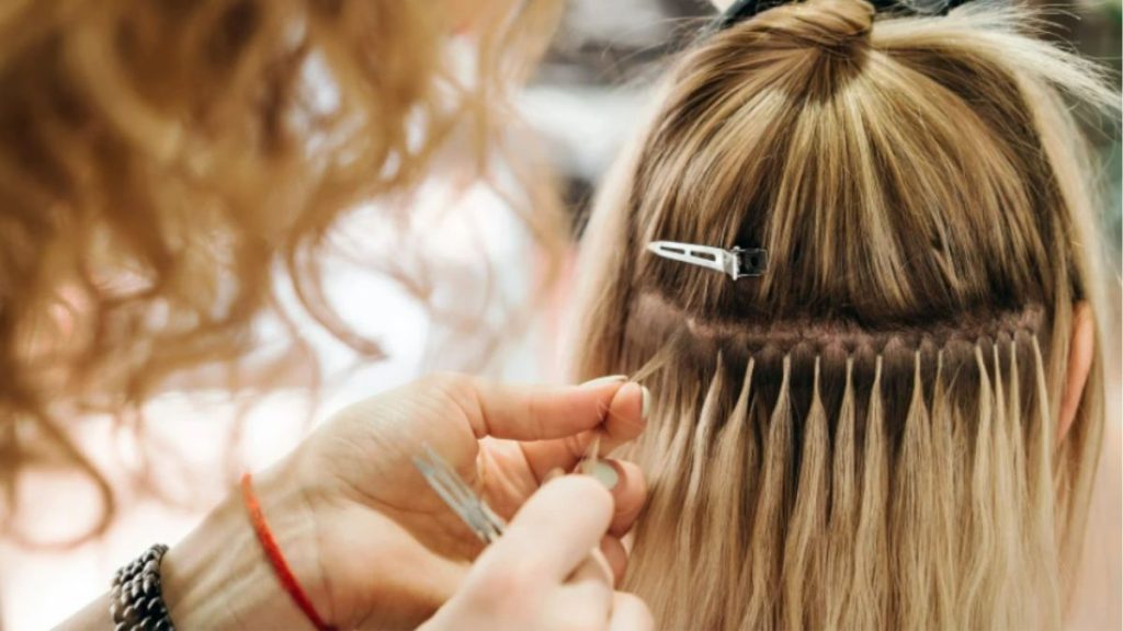 Detalhe de procedimento de manutenção de mega hair em mechas de cabelo, ilustrando o tipo de alongamento capilar proibido pelos protocolos de segurança prisional.