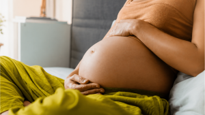 Mãe segurando seu bebê recém-nascido no colo em um ambiente acolhedor, simbolizando a segurança financeira do salário-maternidade garantido por lei.