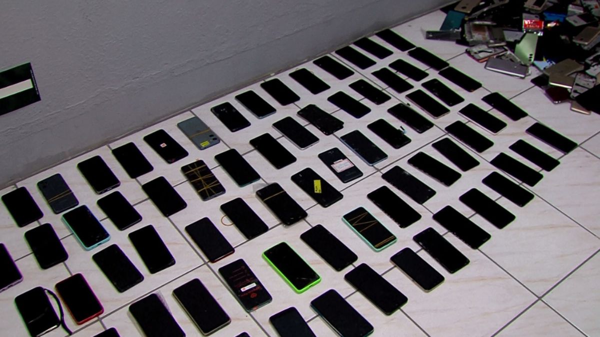 Grande quantidade de aparelhos celulares apreendidos pela Polícia Civil organizados sobre uma mesa durante a Operação Linha Segura na Baixada Santista.