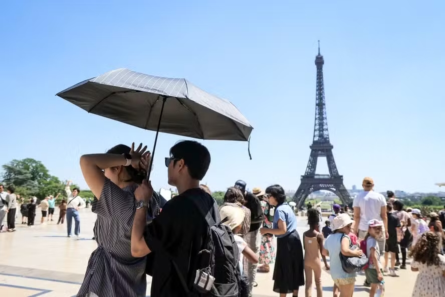 Pessoas caminhando em Paris sob sol intenso durante o segundo nível de alerta para altas temperaturas na capital francesa.