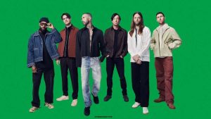 Integrantes da banda Maroon 5, com o vocalista Adam Levine em destaque no palco, representando o anúncio de shows extras em São Paulo, Salvador e São José do Rio Preto.