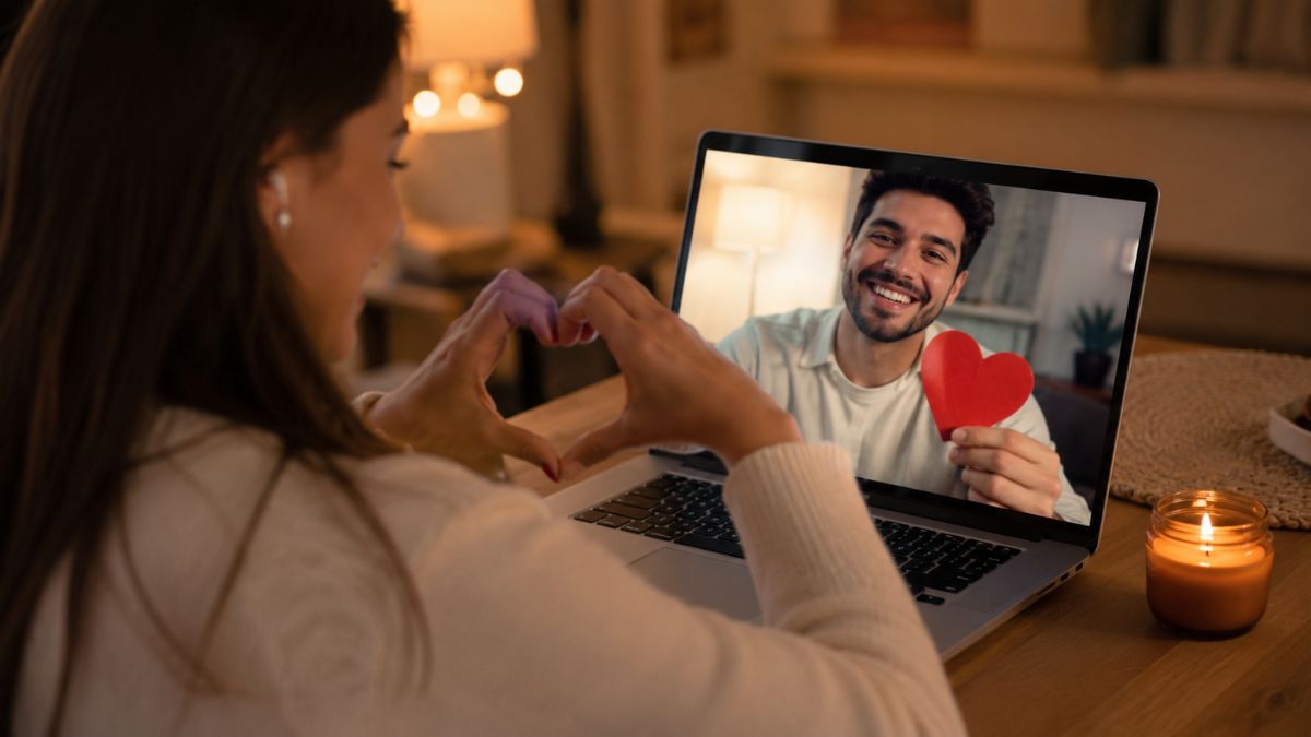 Casal jovem sorridente interagindo com notebook, representando o início de relacionamentos na era digital e o uso de aplicativos de namoro.