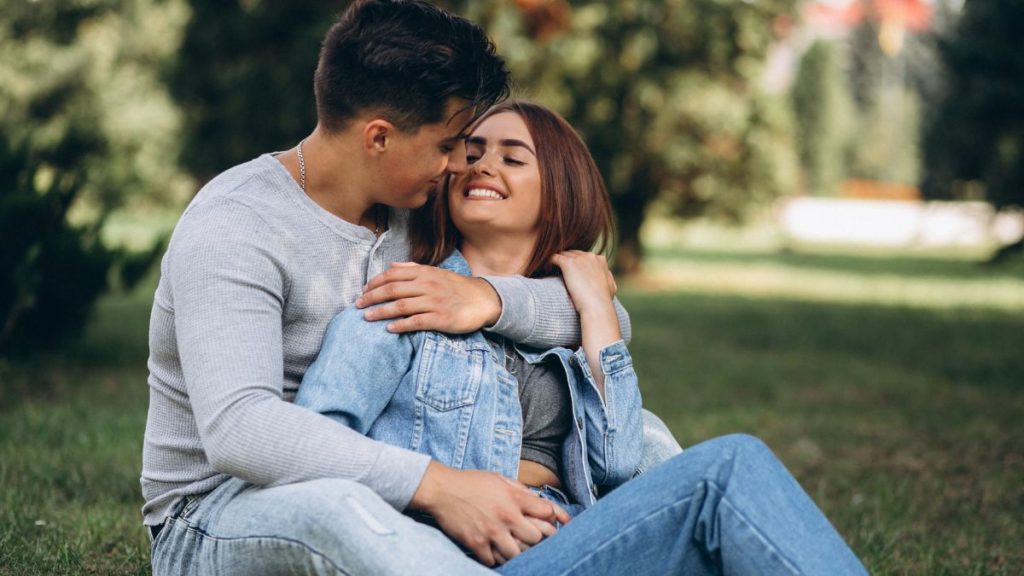 Casal sentado lado a lado compartilhando conteúdo em um smartphone, destacando a nova dinâmica de convivência e interação nos relacionamentos modernos.