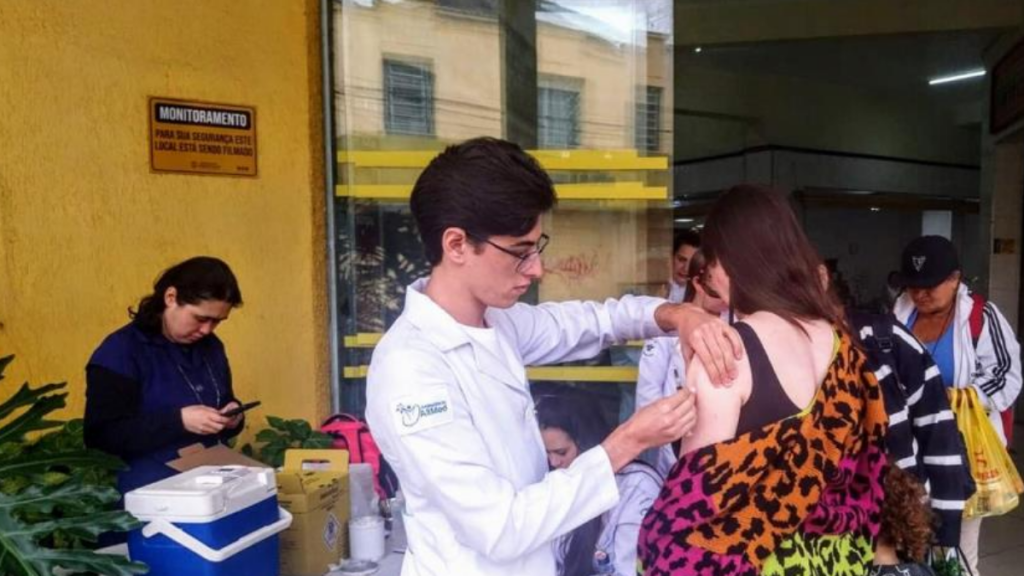 Paciente recebendo dose da vacina contra a gripe no braço em uma unidade de saúde de Bragança Paulista.