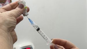 Profissional de saúde aplicando vacina no braço de um paciente durante a campanha de vacinação contra gripe em Indaiatuba.