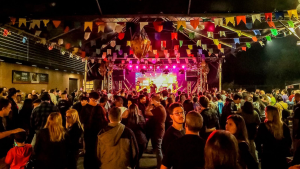 Público celebrando o Arraiá do Prado em Campinas com decoração de bandeirinhas e barracas de comidas típicas em ambiente ao ar livre.
