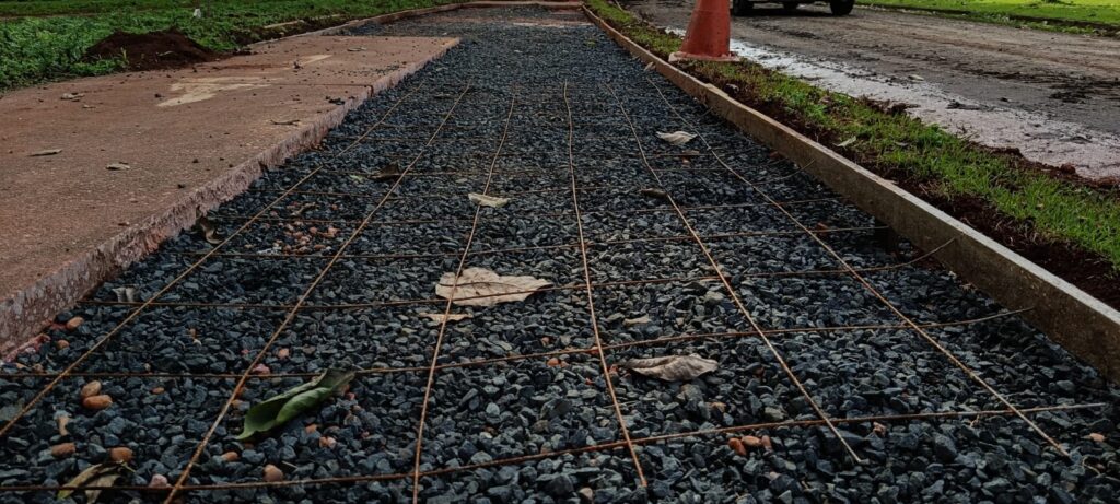 Aplicação de camada de brita e instalação de malha de ferro para reforço estrutural da base da ciclovia em manutenção no bairro Nova Piracicaba.