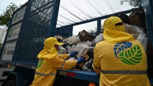 Caminhão de lixo da coleta seletiva de Santos circulando em via urbana para o recolhimento de materiais recicláveis.