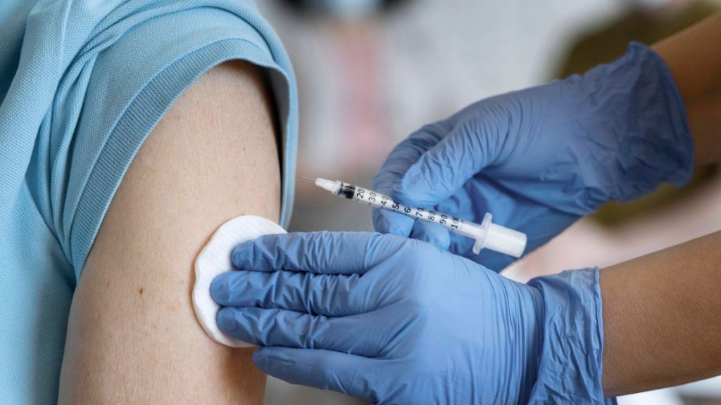 Profissional de saúde aplicando vacina no braço de um paciente durante a campanha de vacinação contra a gripe e o Dia D em Vinhedo.
