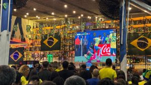 Torcedores assistem a telão no Terminal Central em Campinas durante dia de jogo da Copa, com policiamento e apoio para organização do trânsito e acesso ao transporte público à noite.