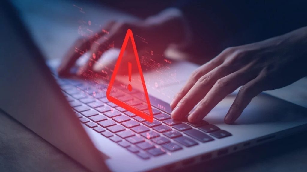 notebook sendo utilizado por uma pessoa com símbolo dealerta para fraudes e golpes pela internet