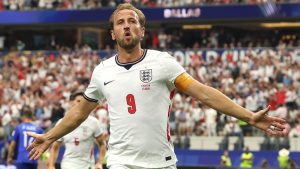 Kane em campo com a camisa da seleção da Inglaterra, comemorando com os braços abertos após gol; imagem destaca Kane iguala recorde histórico e mira marcas de Pelé