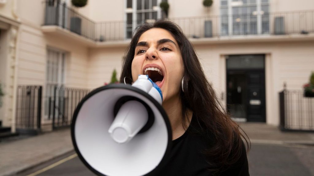 Mulher gritando ao megafone sobre o Dia Internacional do Discurso de odio nas redes sociais