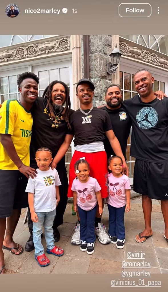 Vini Jr. posa em família em frente a um castelo, ao lado de crianças e adultos, em uma foto na entrada do imóvel nos EUA.
