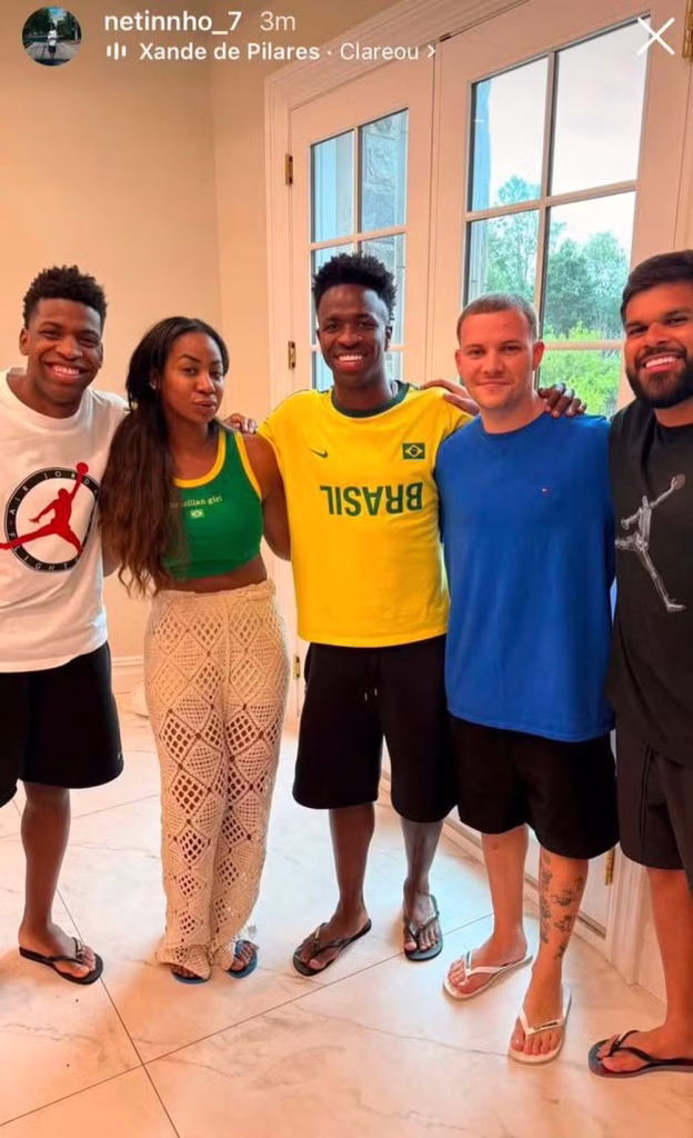 Vini Jr, em frente ao grupo de familiares e amigos dentro de um castelo, sorrindo para a foto em uma visita na área externa, em registro na mesma foto.