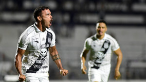Willian Pottker Ponte Preta em campo durante jogo, com expressão intensa e braços abertos, enquanto jogador do clube aparece desfocado ao fundo