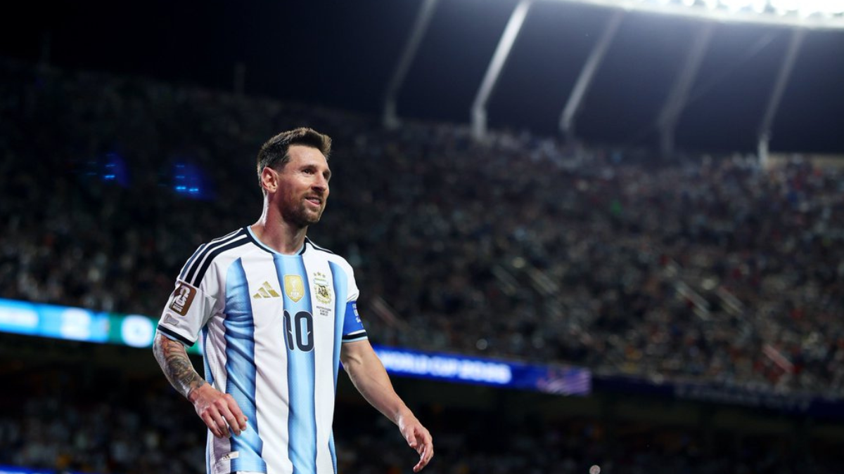Imagem de Lionel Messi em campo durante partida de futebol, usando a camisa da Argentina, diante de um estádio lotado; destaque para a programação de jogos da Copa hoje.