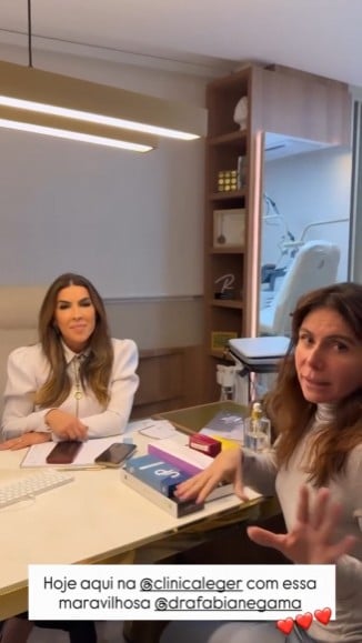 Giovanna Antonelli em uma clínica durante entrevista, sentada à mesa com profissionais em ambiente de consultório, falando sobre procedimento e envelhecimento.