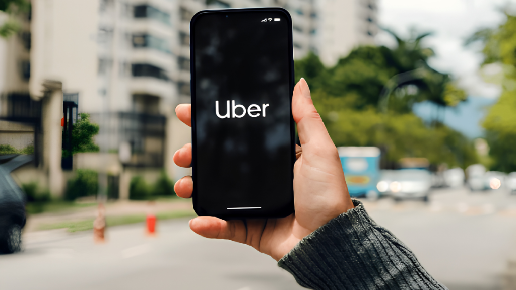 Pessoa segura um smartphone com o logo da Uber na tela, em via urbana com carros ao fundo, destacando as categorias premium como Uber Black e Comfort e atualizações de exigências para melhorar a experiência.