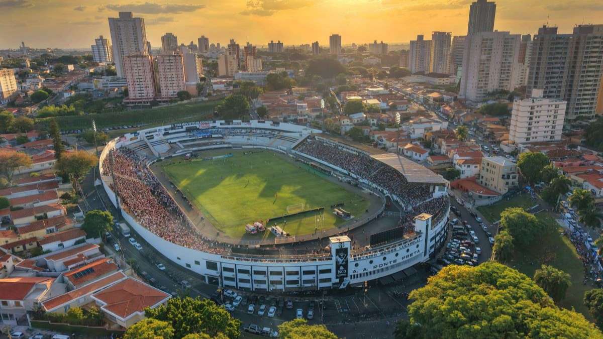 Vista aérea do estádio em Campinas durante partida, com veículos e ruas ao redor; Ponte Preta x Náutico terá bloqueios de trânsito em Campinas nesta sexta (14).