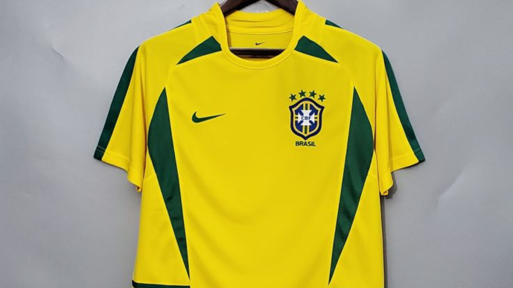 Camisa do Brasil de 2002 amarela com detalhes em verde, escudo da CBF no peito e logotipo da Nike; foto em fundo neutro, vista frontal.