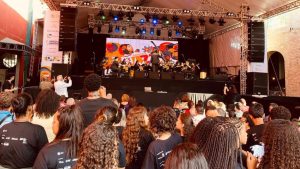 Santos Jazz Festival 2026 em palco ao ar livre com banda tocando, telão com arte musical e plateia lotada em evento de jazz nos espaços do festival, com clima de show gratuito.