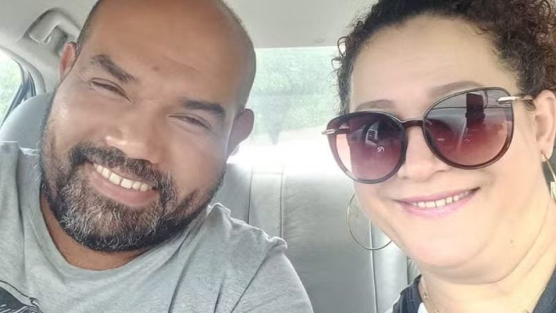 Casal de vinhedo em foto no carro, sorrindo e usando óculos escuros, em viagem. Imagem mostra um homem de barba e uma mulher com cabelo preso, retratando a proximidade do casal.