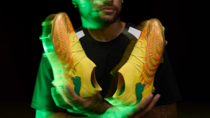 Neymar com chuteira amarela exclusiva, em destaque durante sessão promocional, com iluminação verde e textura detalhada na chuteira, remetendo à volta à Seleção Brasileira.