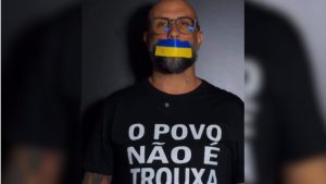 Tiago Peretto cassado aparece em foto de perfil, usando máscara com cores da bandeira da Ucrânia e óculos, com camiseta escrita “O POVO NÃO É TROUXA”.