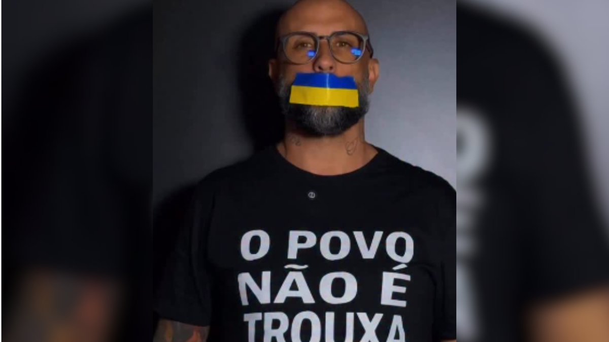 Tiago Peretto cassado aparece em foto de perfil, usando máscara com cores da bandeira da Ucrânia e óculos, com camiseta escrita “O POVO NÃO É TROUXA”.