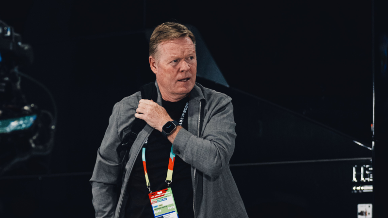 Técnico da Holanda em entrevista ou coletiva, em ambiente esportivo, usando credencial e microfone no pescoço, falando confiante sobre enfrentar o Brasil na Copa.