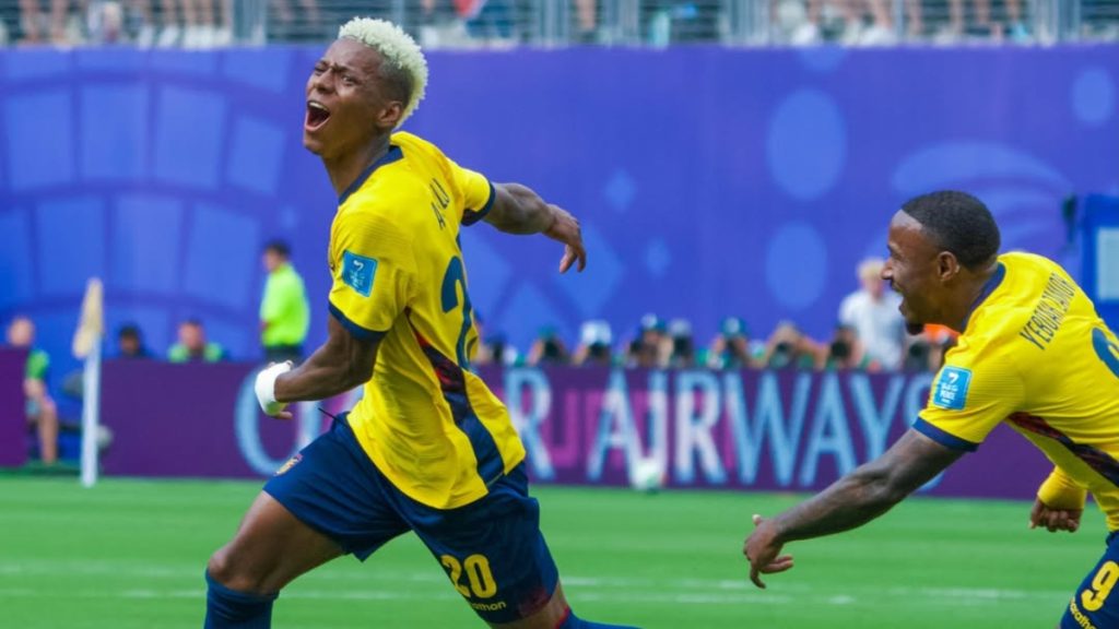 Jogadores do Equador em campo durante partida do Mundial, com atletas em destaque usando camisas amarelas e azuis, celebrando o avanço no mata-mata após vitória sobre a Alemanha
