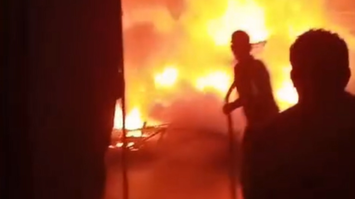 Incêndio shopping Guarujá: silhuetas de pessoas diante de grande labareda e fumaça em um momento de emergência, com fogo iluminando o ambiente ao fundo.