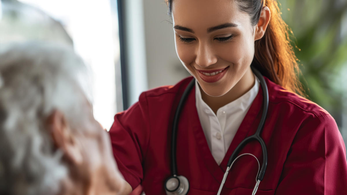 Médica em atendimento de saúde em Sumaré, com estetoscópio e jaleco vermelho, acompanhando paciente em ambiente clínico; ação especial em seis unidades.