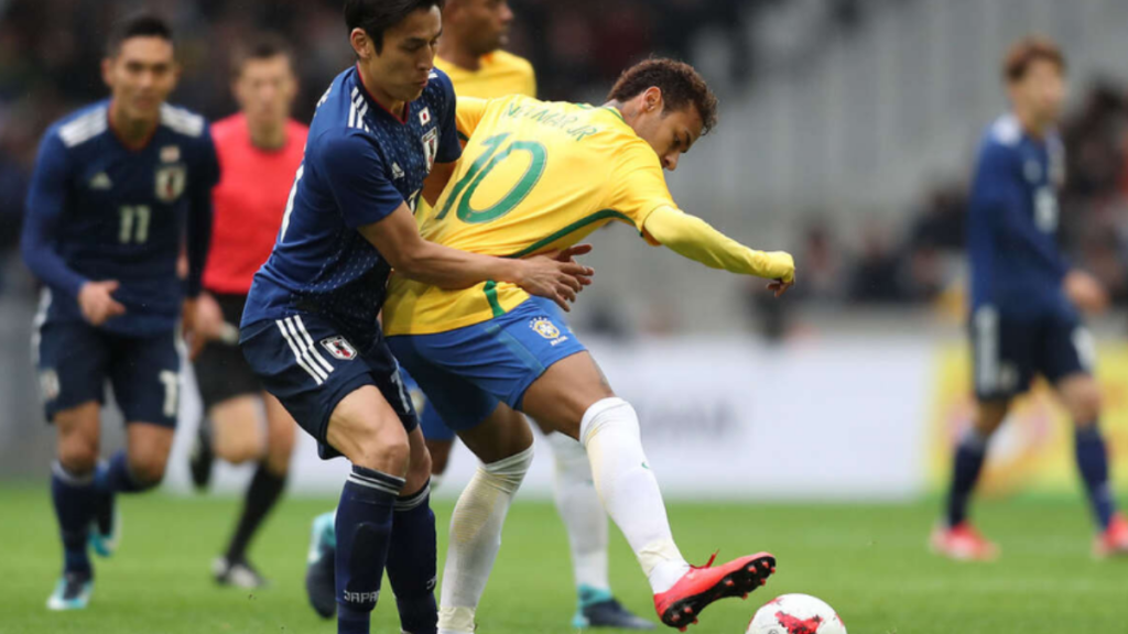 Jogadores de futebol em partida da Seleção Brasileira, com atletas disputando a bola em campo, destacando o expediente público no jogo do Brasil e a adaptação de horários para acompanhar a Copa do Mundo 2026.
