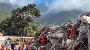 Imagem mostra equipes de resgate trabalhando entre escombros e prédios danificados após terremotos na Venezuela, em contexto de Alerta OMS Venezuela sobre colapso do sistema de saúde.