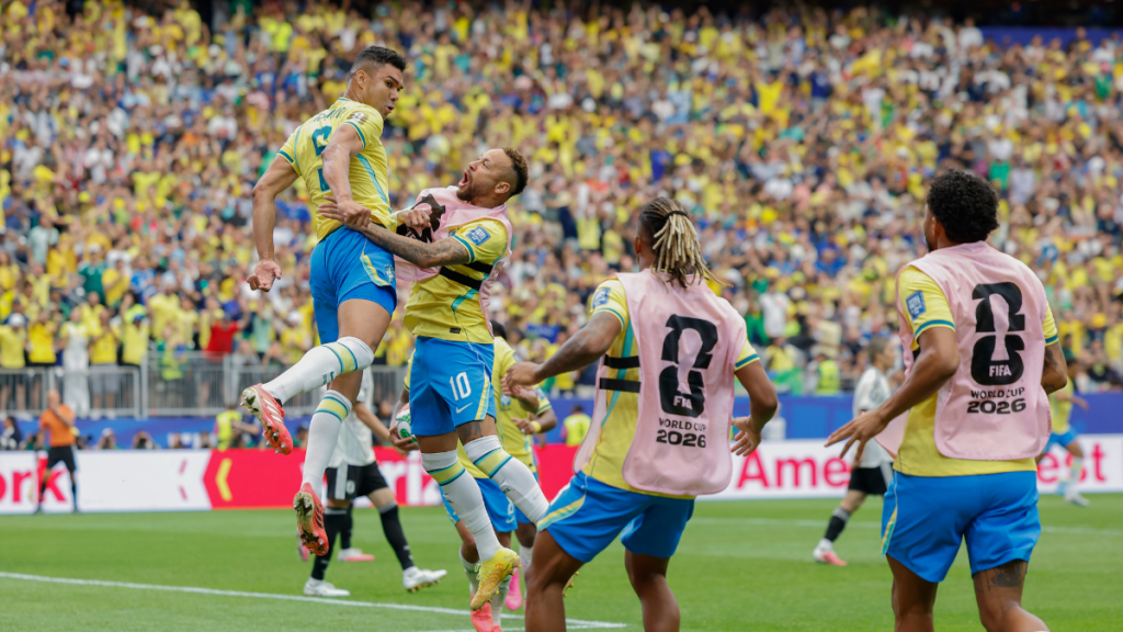 Seleção brasileira: Casemiro comemora gol em partida contra o Japão, em clima de oitavas de final, com jogadores celebrando no estádio lotado e camisa da FIFA World Cup 2026.