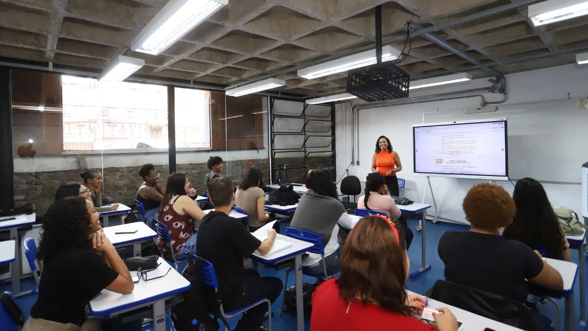 Sala de aula com alunos sentados em carteiras e uma instrutora apresentando conteúdo em lousa e telão, ilustrando vagas ceprocamp em cursos gratuitos de qualificação em Campinas.