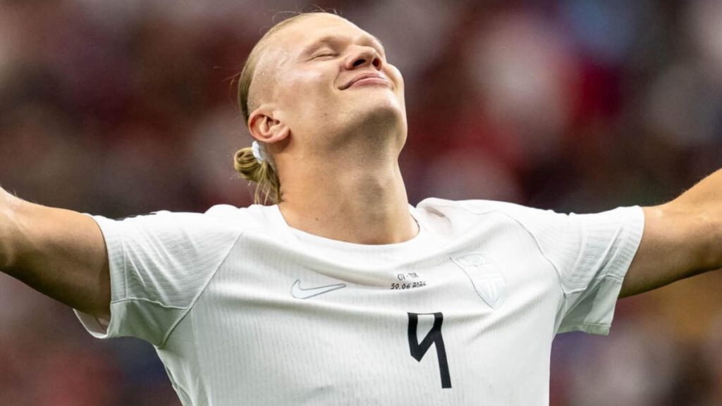 Haaland comemora em campo com a camisa da Noruega, braços abertos, após decidir o jogo no fim contra a Costa do Marfim e classificar a Noruega para enfrentar o Brasil.