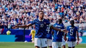 Mbappé comemora em campo pela seleção francesa, com braços abertos, durante partida da Copa do Mundo. Ao fundo, jogadores da França em um estádio lotado.