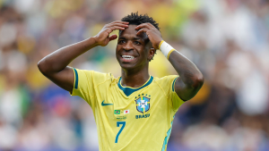 Jogador da seleção brasileira em campo, com a camisa amarela e a mão formando um gesto na cabeça, em partida no estádio; Brasil x Noruega pela Copa