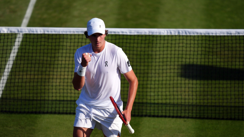 João Fonseca em partida no Wimbledon, em quadra de grama, segurando a raquete e preparando o golpe com foco no jogo enquanto busca a vitória e avanço na terceira rodada.